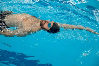 Yüzme. Siyah yüzme şapkalı bir adam havuzda yüzüyor.