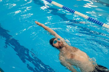 Yüzme. Siyah yüzme şapkalı bir adam havuzda yüzüyor.