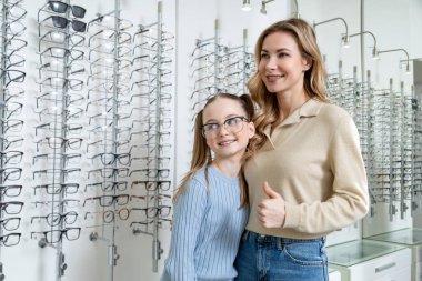 Yeni gözlük. Anne ve kızı optik dükkanında yeni gözlük seçtikten sonra pozitif görünüyor.