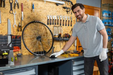 Atölye ortamında bisiklet tekerleğini denetleyen beyaz eldivenli bir tamirci.