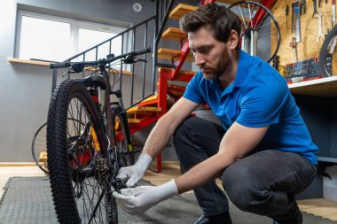 Tamirci atölyede bisiklet tekeriyle poz veriyor, uzmanlık gösteriyor.