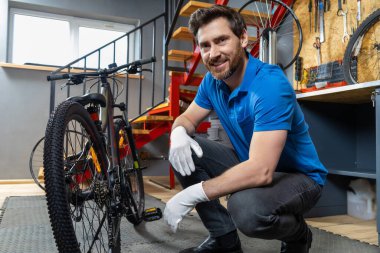 Tamirci atölyede eldivenli ellerle bisiklet tekerleğini ayarlıyor