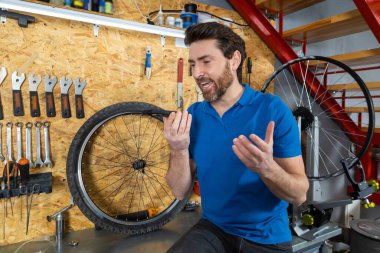 Mavi gömlekli tamirci atölyedeki araçların yanındaki cihaza sesli mesaj kaydediyor.