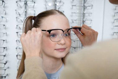 Yeni gözlük. Anne optik dükkanından küçük tatlı kızı için yeni gözlük seçiyor.