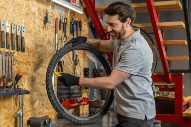 Atölye ortamında siyah eldivenli tamirci bisiklet tekerleğini kaldırıyor