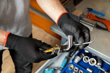 Siyah eldivenli tanınmayan tamirci atölye ayarlarında aletlerle çalışıyor