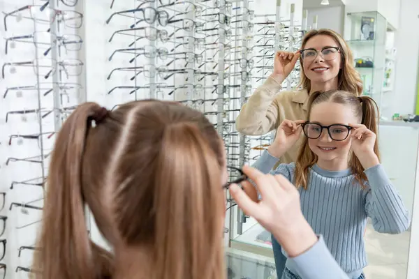Yeni gözlük. Anne optik dükkanından küçük tatlı kızı için yeni gözlük seçiyor.