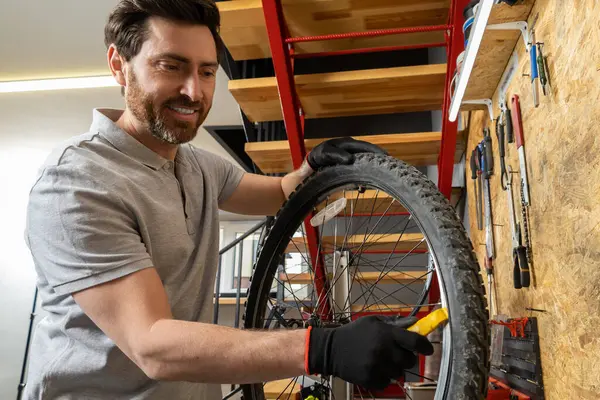 Siyah eldivenli tamirci atölyede aletlerle bisiklet tekerleğini tutuyor.