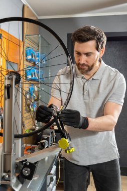 Atölye ortamında siyah eldivenli tamirci bisiklet tekerleğini kaldırıyor