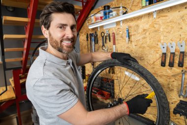 Siyah eldivenli tamirci atölye ortamında bisiklet tekerleğini ayarlıyor
