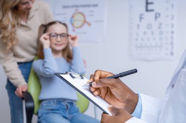 Reçeteli. Küçük bir hastaya reçete yazan göz doktorunun resmini kapat.