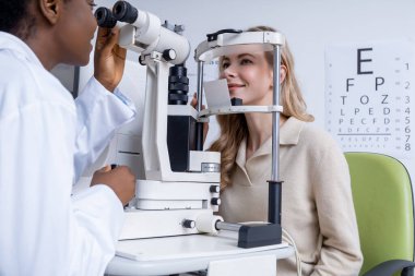 Optometri. Optometriste vizyon muayenesi olan genç bir kadın.