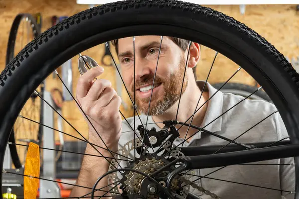 Tamirci atölyede elleri olan bisiklet tekerleğini ayarlıyor