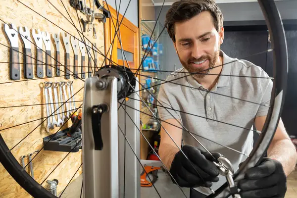 Siyah eldivenli tamirci atölyede bisiklet tekeri üzerinde çalışıyor.