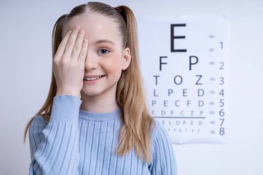 Vizyon testi. Göz hekimliği ofisinde Snellen vizyon testi geçmişi olan beyaz bir kız.