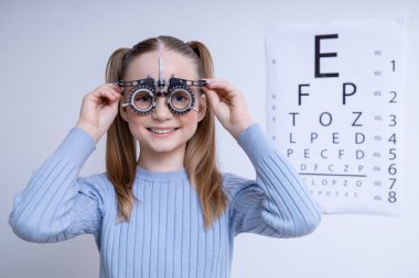 Vizyon testi. Göz hekimliği ofisinde Snellen görme testinde optometrik kadırgaları olan beyaz tatlı bir kız.