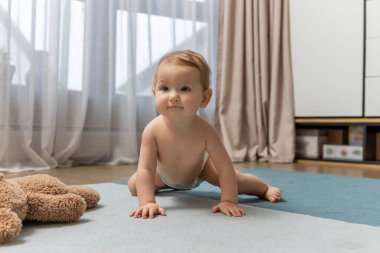 Yerde sürünen tatlı bir oğlan çocuğu ve mutlu görünüyor.