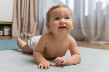 Yerde sürünen tatlı bir oğlan çocuğu ve mutlu görünüyor.