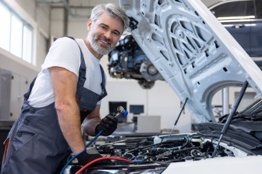 Tamirci, otomatik tamir atölyesinde dizüstü bilgisayarlı araç kutusundan araç seçiyor