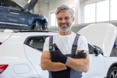 Tamirhanedeki atölyede kolları çaprazlanmış bir tamirci.