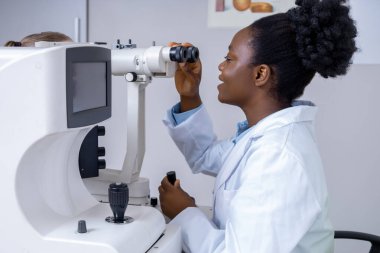 Optik ekipman. Hasta ile çalışırken optik tıbbi araç kullanan kadın göz doktoru