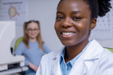 İşteki doktor. Ofisinde çalışan Afro-Amerikan kadın göz doktoru.