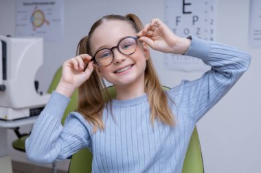Yeni gözlük. Gözlüklü sevimli beyaz kız olumlu ve memnun görünüyor.