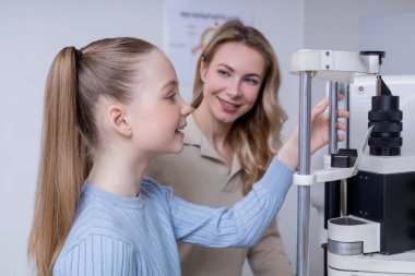 Vizyon testi. Sarışın bir kız ve annesi göz doktorunda danışmanlık yapıyorlar.
