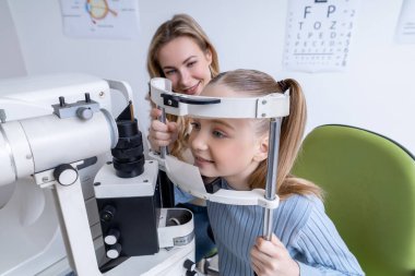 Vizyon testi. Sarışın bir kız ve annesi göz doktorunda danışmanlık yapıyorlar.