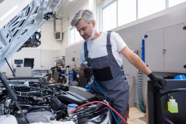 Tamirci, otomatik tamir atölyesinde dizüstü bilgisayarlı araç kutusundan araç seçiyor