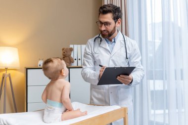 Doktorlarda. Çocuk doktoru, ofisinde küçük sevimli bir çocuğu muayene ediyor.