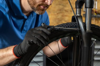 Tamirhanecilerin elleri tamirhanenin yanında aletlerle bisiklet tekerleği üzerinde çalışıyor.