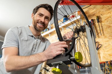 Atölye ortamında beyaz eldivenli tamirci bisiklet tekerleğini kaldırıyor