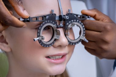 Optometrik araç. Doktor bir kızın görme yeteneğini test ederken optometrik aracı ayarlıyor