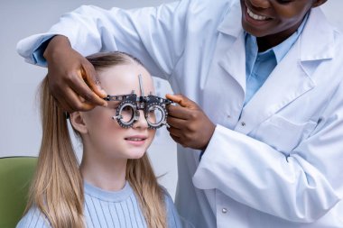 Optometrik araç. Doktor bir kızın görme yeteneğini test ederken optometrik aracı ayarlıyor