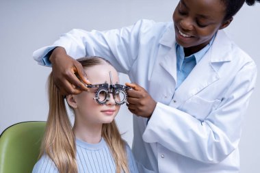 Optometrik araç. Doktor bir kızın görme yeteneğini test ederken optometrik aracı ayarlıyor