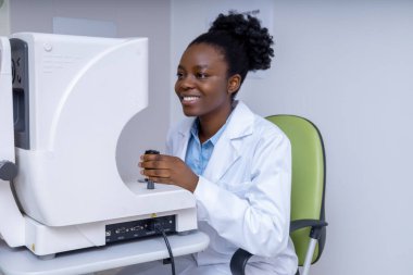 Optometrist iş başında. Ofisinde çalışan gülümseyen Afro-Amerikan optometrist