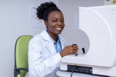 Optometrist iş başında. Ofisinde çalışan gülümseyen Afro-Amerikan optometrist