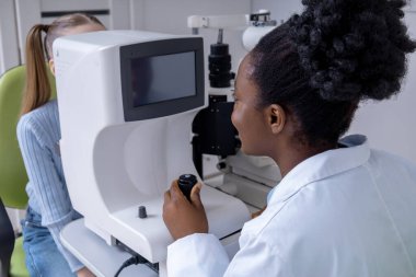 Optometrist iş başında. Ofisinde çalışan gülümseyen Afro-Amerikan optometrist
