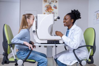 Görüş kontrolü. Doktor tıbbi ekipman kullanarak bir kızın görüntüsünü kontrol ediyor.