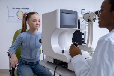 Görüş kontrolü. Doktor tıbbi ekipman kullanarak bir kızın görüntüsünü kontrol ediyor.