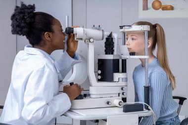 Vizyon sınavı. Optik tıbbi ekipman kullanarak kız görüşünü kontrol eden oftalmolog