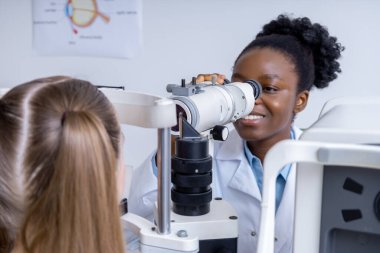 Optik ekipman. Hasta ile çalışırken optik tıbbi araç kullanan kadın göz doktoru