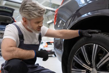 Tamircide çömelirken, mekanik teftiş tekerleği