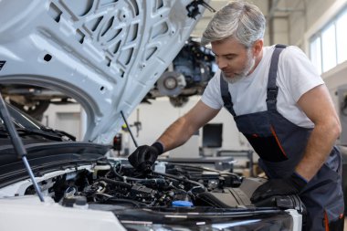 Motor yağı seviyesini otomatik tamir atölyesinde kaput açık dipstick ile kontrol eden tamirci