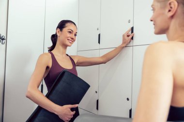 Sohbet. Spor salonunda soyunma odasında konuşan iki genç kadın.