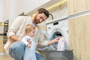 Yıkama hazırlığı. Genç adam ve küçük oğlu çamaşır makinesine koymadan önce elbiselerini ayırıyorlar.