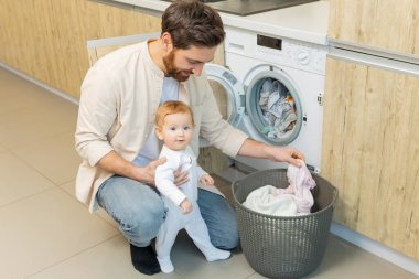 Yıkama hazırlığı. Genç adam ve küçük oğlu çamaşır makinesine koymadan önce elbiselerini ayırıyorlar.