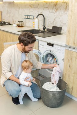 Yıkama hazırlığı. Genç adam ve küçük oğlu çamaşır makinesine koymadan önce elbiselerini ayırıyorlar.