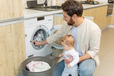 Yıkama hazırlığı. Genç adam ve küçük oğlu çamaşır makinesine koymadan önce elbiselerini ayırıyorlar.